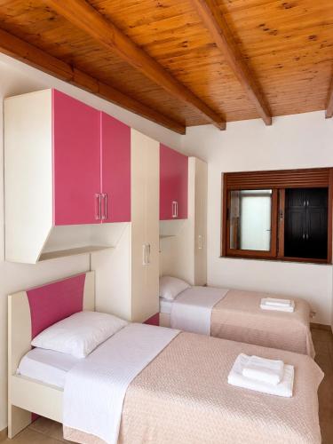 two beds in a room with pink and white cabinets at Terminal Comfort Apartament in Tirana