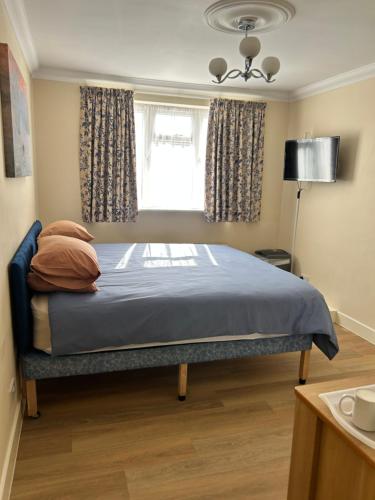 a bedroom with a bed with a blue blanket and a window at Montrose Guest House in Romford