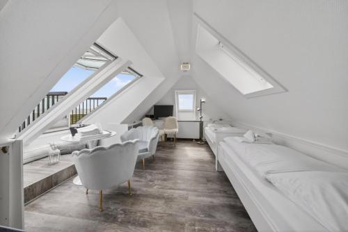 a living room with white furniture and windows at Gurtdeel 1000 Sterne-Suite in Hörnum
