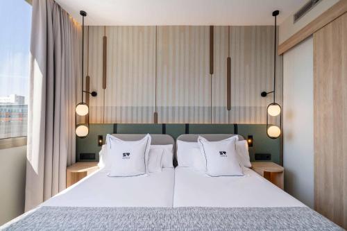 a bedroom with a large bed with white pillows at Hotel & Spa Villa Olimpica Suites in Barcelona