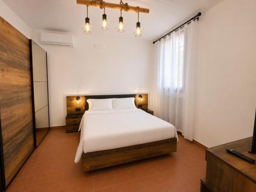 a bedroom with a white bed and a television at B&B La Vigna dei Fratelli in lido degli scacchi