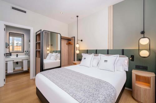 a bedroom with a large white bed and a bathroom at Hotel & Spa Villa Olimpica Suites in Barcelona