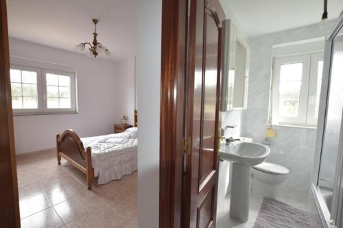 a bathroom with a sink and a bedroom with a bed at Casa Emiliano in Cee