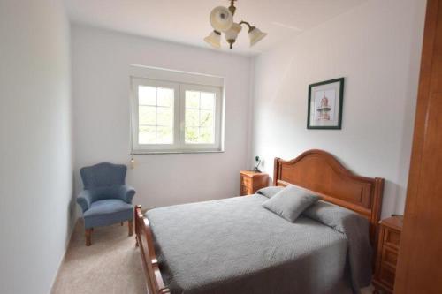 a bedroom with a bed and a blue chair at Casa Emiliano in Cee
