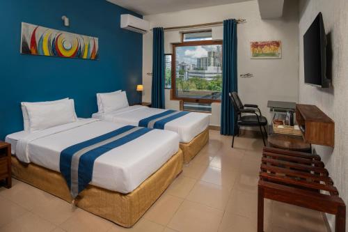 a hotel room with two beds and a desk and a window at Hotel Raha Tower in Dar es Salaam