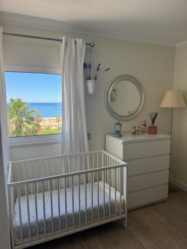 a nursery with a crib and a window with the ocean at Apartamento Deluxe AM in Quarteira