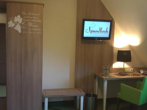 um quarto com uma televisão na parede e uma mesa em Spundloch- das Hotel & Weinrestaurant em Veitshöchheim