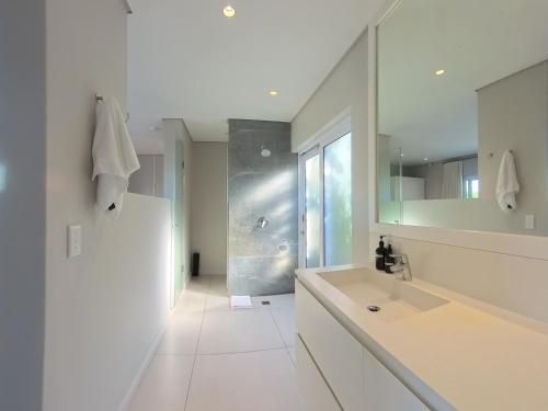 a white bathroom with a sink and a mirror at Betty in Plettenberg Bay