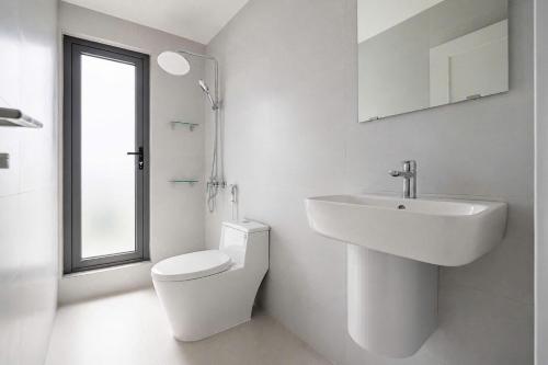 a white bathroom with a sink and a toilet at Savia Home in Danang