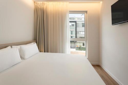 a bedroom with a white bed and a window at B&B HOTEL Covilhã in Covilhã