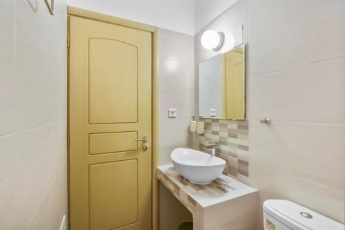 a bathroom with a yellow door and a sink at Salty Wind Antiparos Apartments and Studios in Agios Georgios