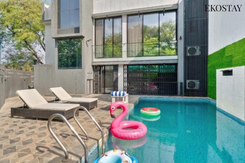 a swimming pool with a pink flamingo toy in front of a house at EKOSTAY - ONYX Villa in Mumbai