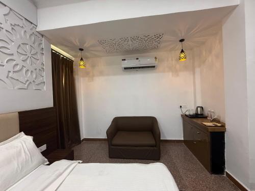 a hotel room with a bed and a chair at Hotel Pratap Palace in Bharatpur