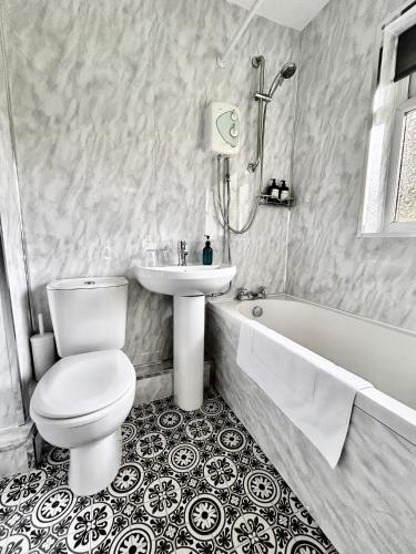 a bathroom with a toilet and a sink and a tub at The Alexandria in Westhoughton