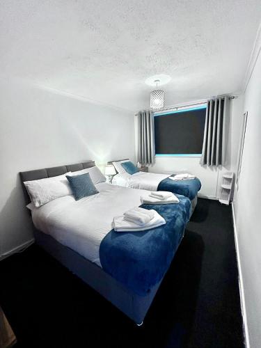 a bedroom with two beds with blue sheets at The Alexandria in Westhoughton