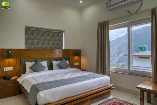 a bedroom with a large bed and a large window at Pacific Inn Vistaar Hotels & Resorts in Chamba