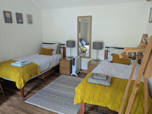 a bedroom with two beds and a mirror at Sunnyside Annexe in Oxford