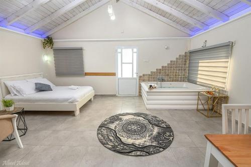 a bedroom with a bed and a bath tub at בקתות לוטן דלתון - 4 בקתות עם ג'קוזי פרטי ו-2 בריכות משותפות in Shahar