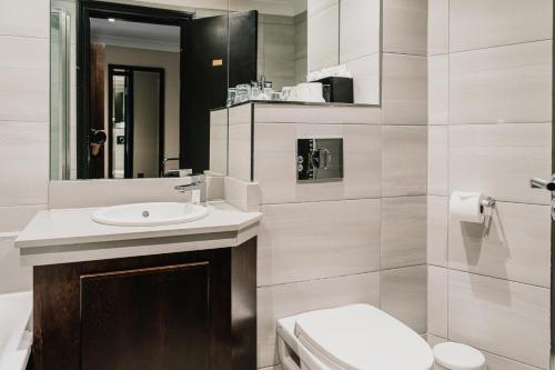 a bathroom with a sink and a toilet and a mirror at The County Hotel Newcastle in Newcastle upon Tyne