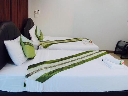 two beds with green and white sheets in a room at Retro Twin Home @Maesot in Mae Sot