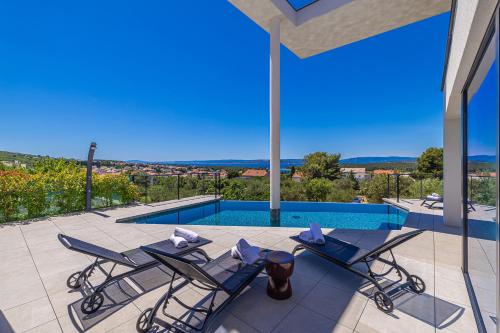 a patio with two chairs and a swimming pool at Luxury villa 45 with infinity pool in Punat