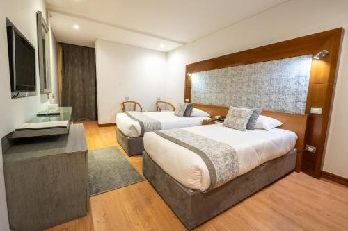 a hotel room with two beds and a flat screen tv at Maadi Hotel in Cairo