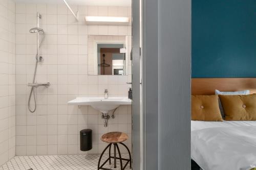 a bathroom with a bed and a sink and a shower at Ibsens Hotel in Copenhagen