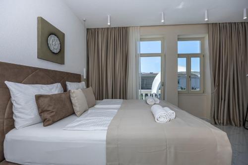 a bedroom with a large white bed with a clock on the wall at Villa Vita luxury Apartments in Crikvenica
