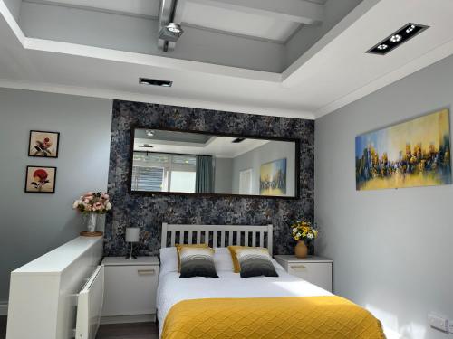 a bedroom with a yellow bed and a mirror at The Welcome Haven - Cozy Studio with Patio & Free Parking in Chislehurst