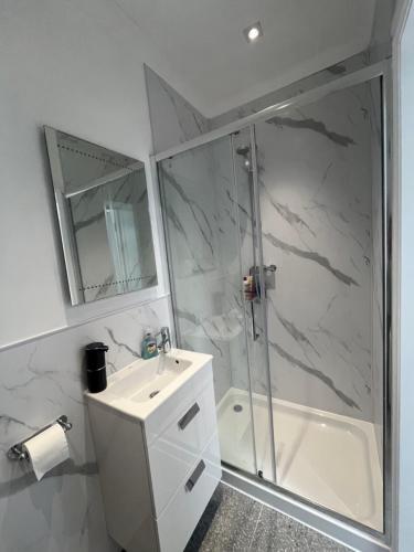 a bathroom with a shower and a sink and a tub at The Welcome Haven - Cozy Studio with Patio & Free Parking in Chislehurst