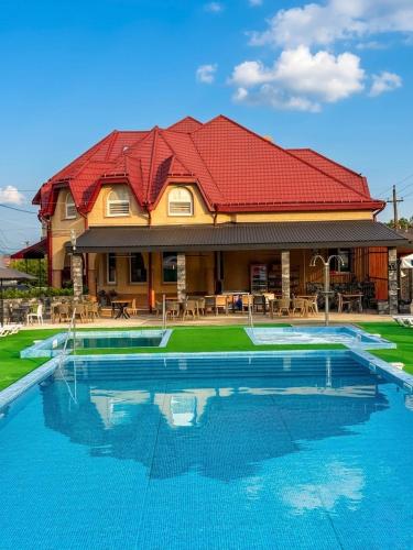 a house with a red roof and a swimming pool at Aqua Hotel in Solotvyno
