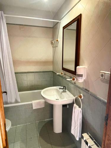 a bathroom with a sink and a bath tub at Hostal Bil in Salduero