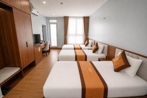 a hotel room with three beds and a television at Eagle Sầm Sơn Hotel in Sầm Sơn