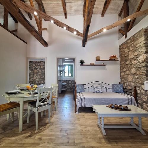 a bedroom with a bed and a table and a dining room at Alekos Cozy Stone 2BR Home Karya Center in Lefkada