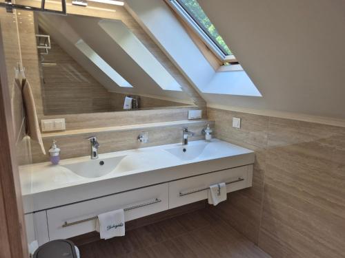 a bathroom with a sink and a skylight at Platán Panzió in Dobogoko