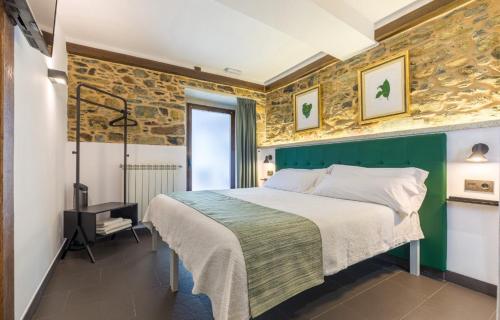 a bedroom with a large bed and a stone wall at Albergue O Candil in Melide