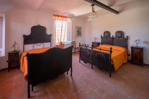 two beds in a room with orange sheets at B&B Anima Selvaggia Ranch in Castellero