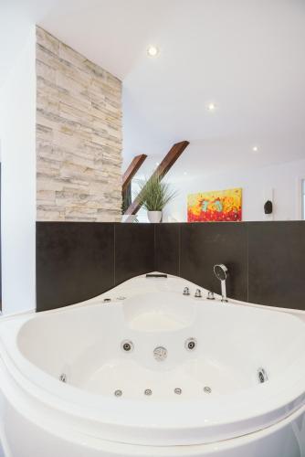 a white bath tub in a bathroom with a stone wall at Hotel Restaurant Pusswald in Hartberg
