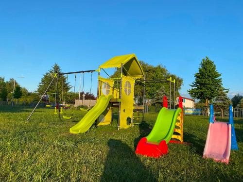 a playground with a slide in the grass at Neptun in Kołobrzeg