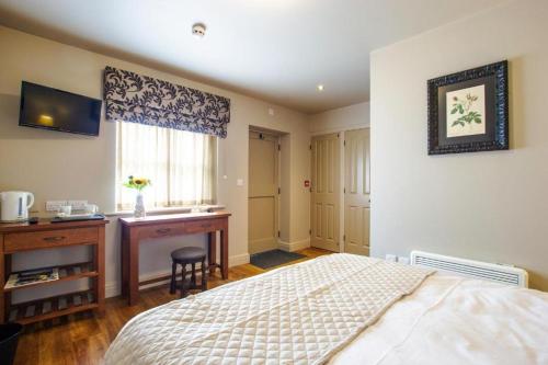 a bedroom with a bed and a desk and a window at The Cherry Tree Rochford in Rochford