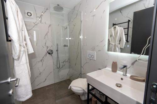 a white bathroom with a shower and a sink at The Olive Garden in Shkodër