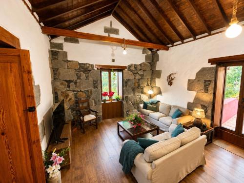 a living room with two couches and a stone wall at Finca La Acequia del Gamonal in Santa Brígida