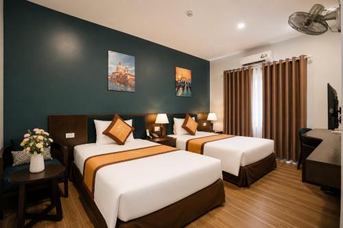 a hotel room with two beds and a desk at Eagle Sầm Sơn Hotel in Sầm Sơn
