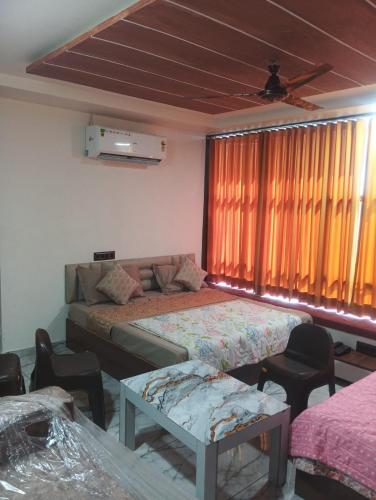 a bedroom with two beds and a couch and a window at hotel shaurya in Naroda