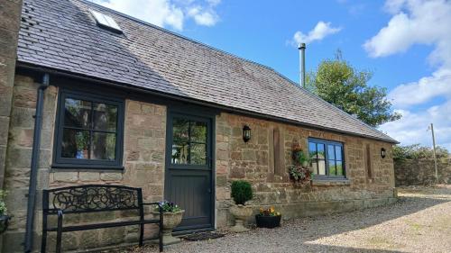 a stone house with a bench in front of it at Stable Lodge in Berwick-Upon-Tweed