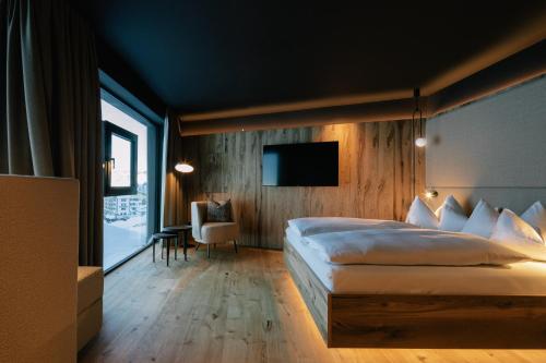 a bedroom with a large bed and a tv at Hotel Steiner Superior in Obertauern