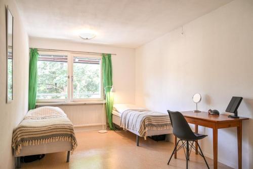 a bedroom with two beds and a desk and a window at Klintehamn Rooms - Near the Sea in Klintehamn