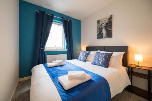 a blue bedroom with a large bed with towels on it at Surfer 2Bed GF Flat Central Thurso, Parking, Fibre in Thurso