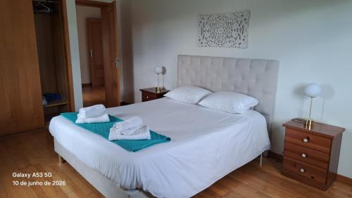 a bedroom with a white bed with towels on it at Apartamento Lombinha in Vila Franca do Campo