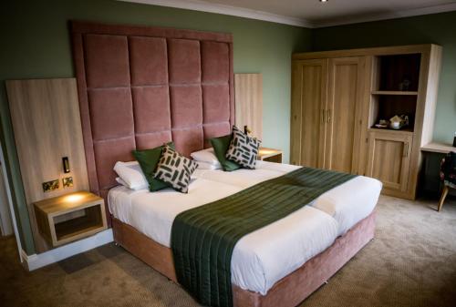 a bedroom with a large bed with a large headboard at Clifton Arms Hotel in Lytham St Annes